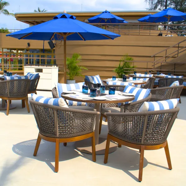 Wooden dining table detail with woven seating at Azura Restaurant in Phuket
