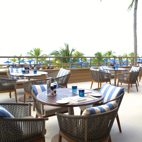 Round dining table set with woven rattan chairs at Azura beachfront